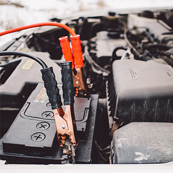 An engine with black and orange jumper cables near it