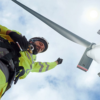 Windmill on top of a male wind turbine technician