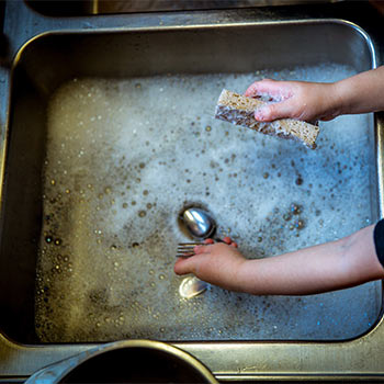 Soapy sink being cleaned by two hands