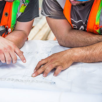 Construction plan under the hands of two men