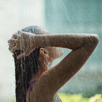 Showering woman holding her head