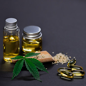 CBD leaf with yellow bottles and pills in the background